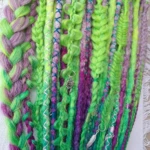 Dreadlocks synthétiques vertes et violettes avec des motifs tressés.